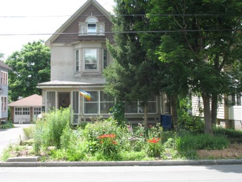Residential house with lush garden and trees in a neighborhood setting.