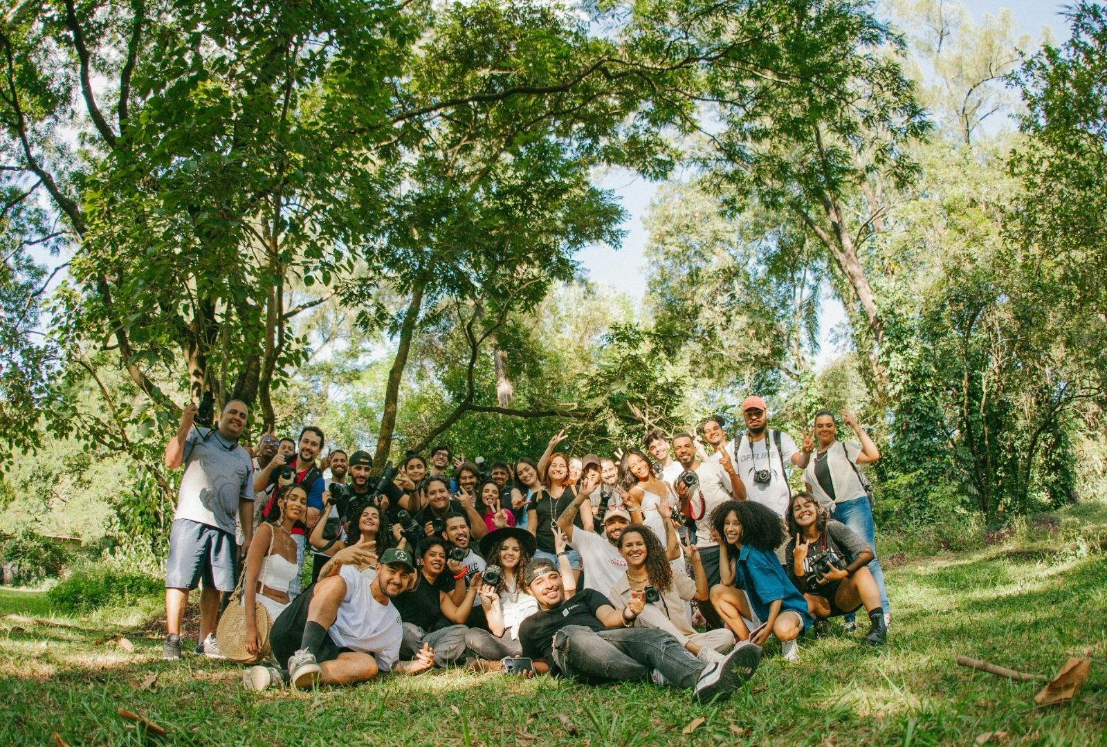 Group of diverse people outdoors in a green park, smiling and celebrating together.