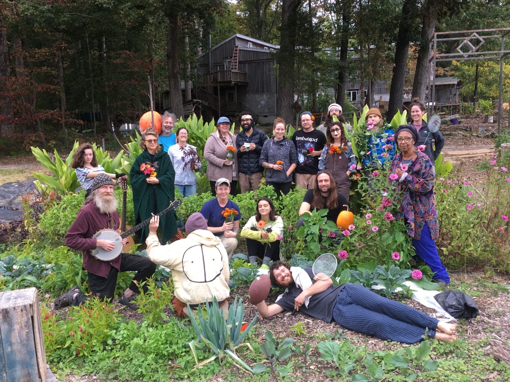 Group of people in a garden with flowers and trees at Acorn Community Farm.