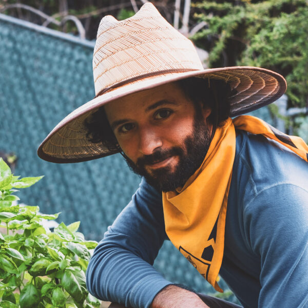 Person in a straw hat gardening at Foundation for Intentional Community.