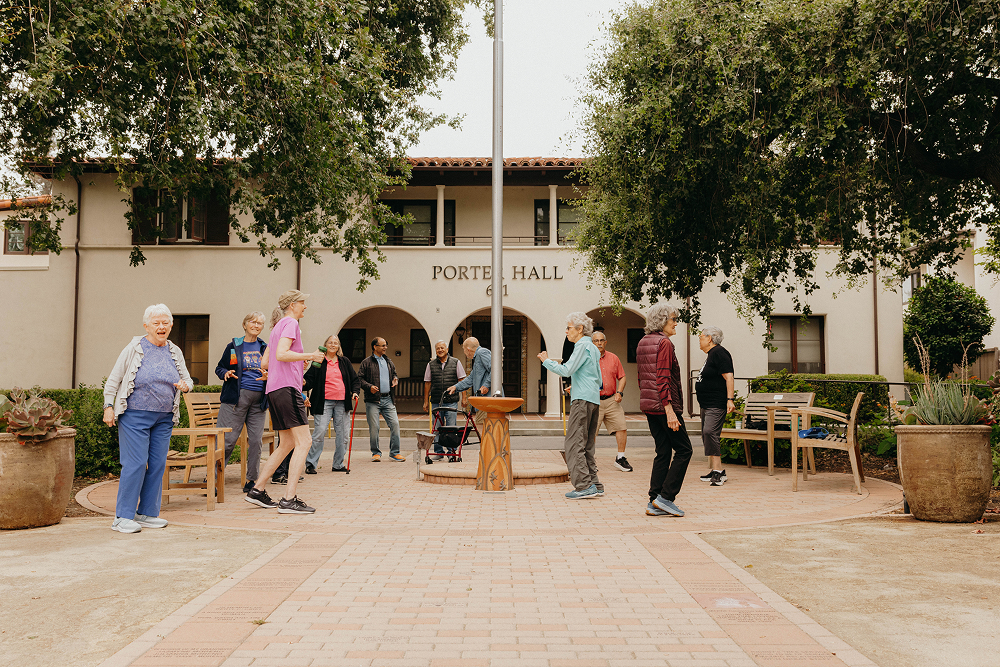 Group of diverse seniors socializing outside Porte Hall building.