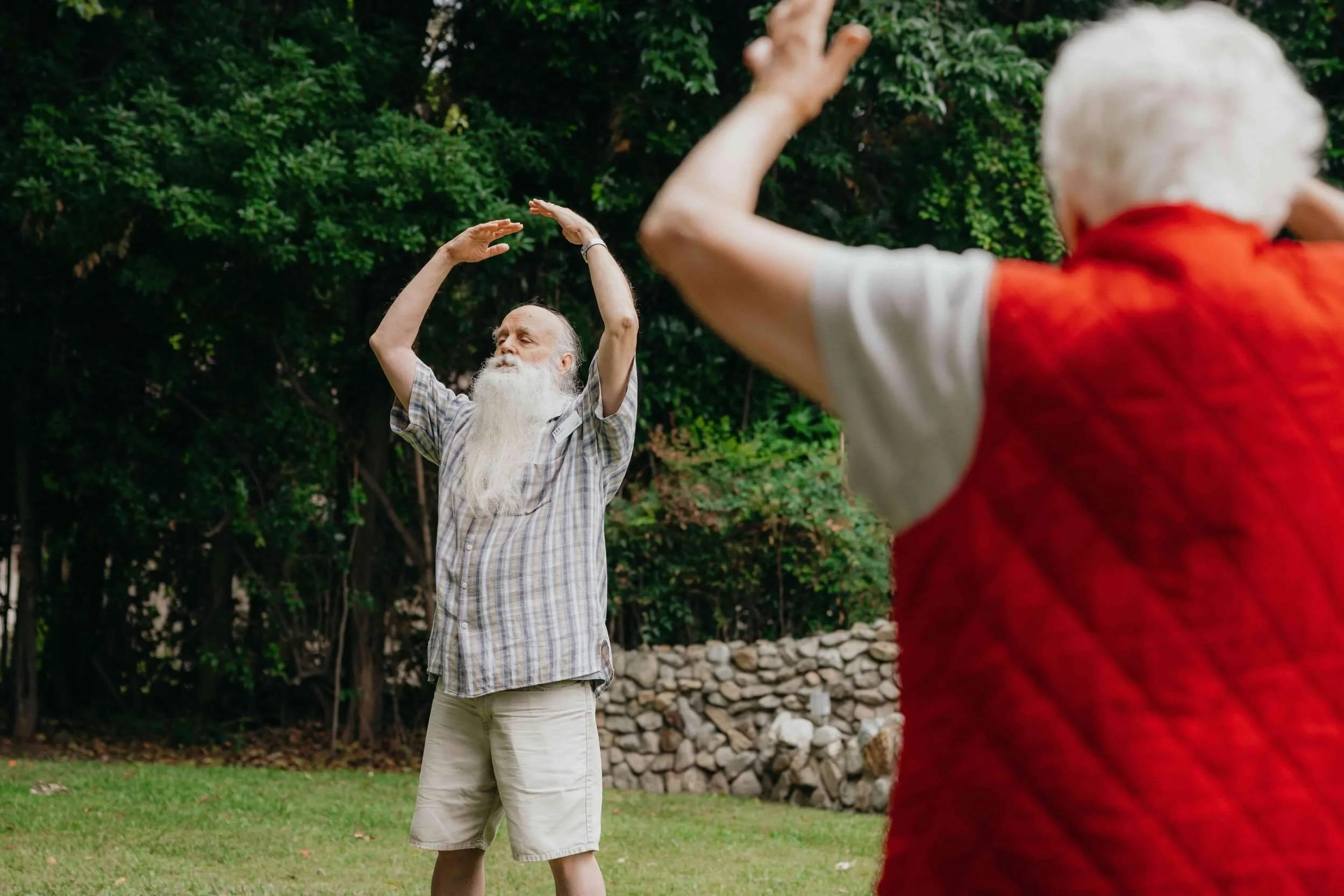 Older adults enjoying outdoor exercise in a green park setting.