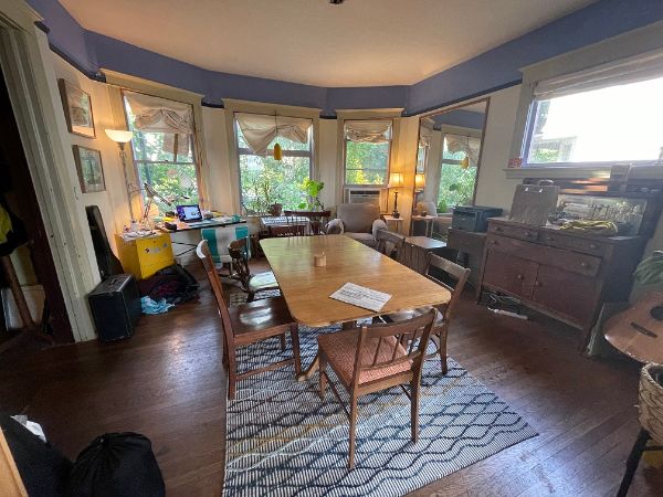 Cozy community room with large bay windows and wooden furniture.